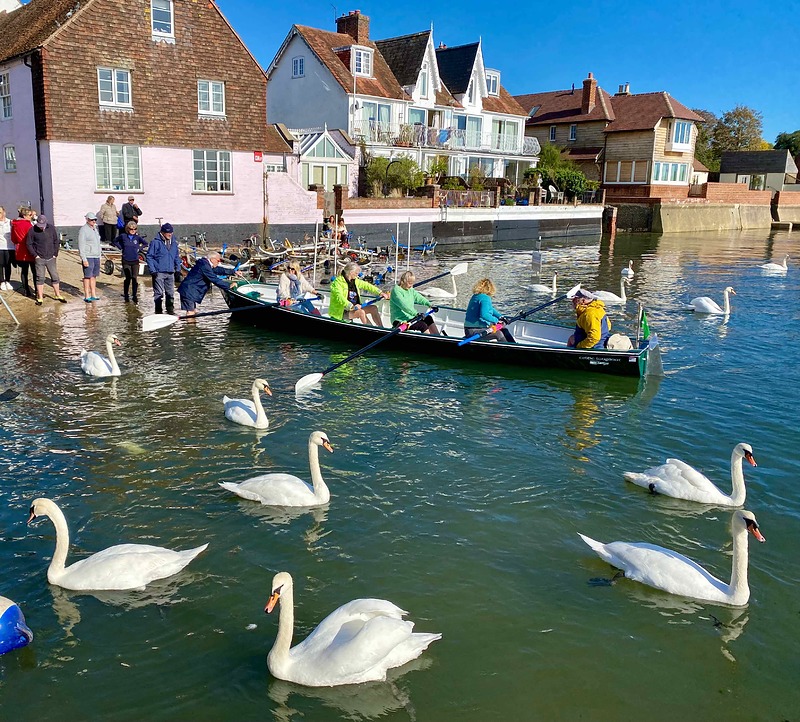 Five people in a rowing boat depar from the Emsworth Slipper Sailing Club