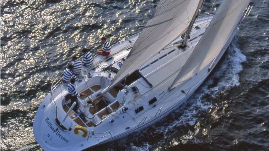 Five sailors in striped shirts sit aboard a First 45f5 on the open sea