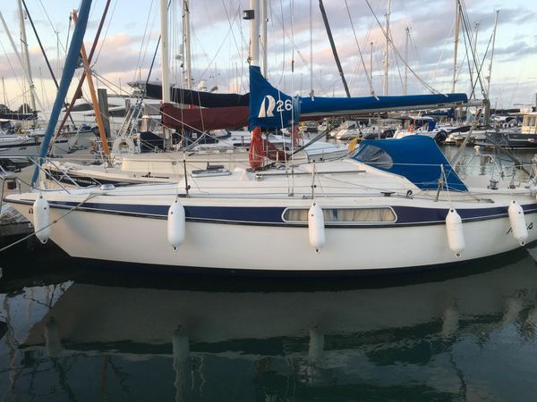 A white and blue Hallberg Rassy 26 is moored in Southampton Marina