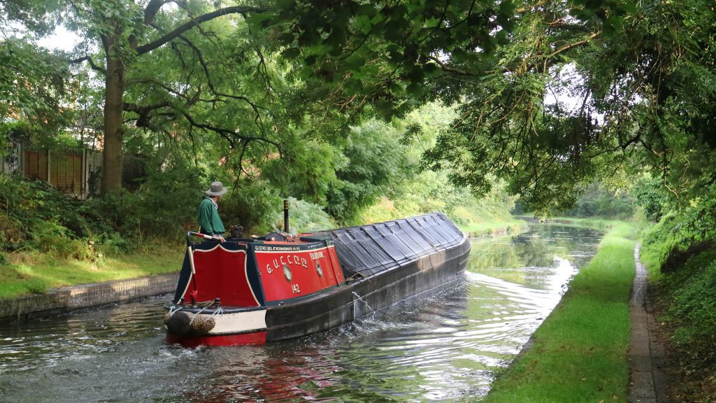A traditional narrowboat cruises down a British canal | Image by Tim Lewis on Unsplash