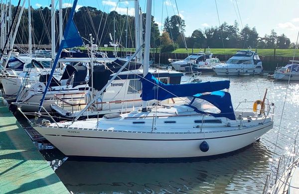 A white and blue Sadler 32 sailing boat is moored in woodbridge harbour