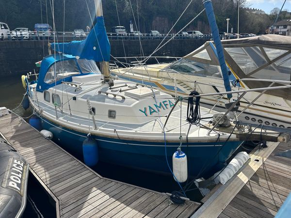 A white and blue Westerly is moored in a harbour